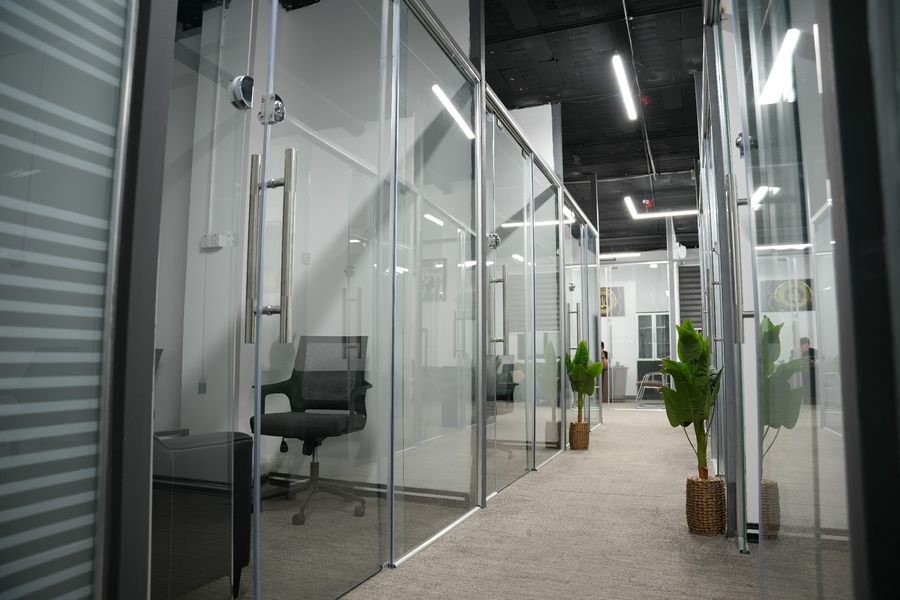 Glass-walled private offices along a corridor inside Business Hub, Basra